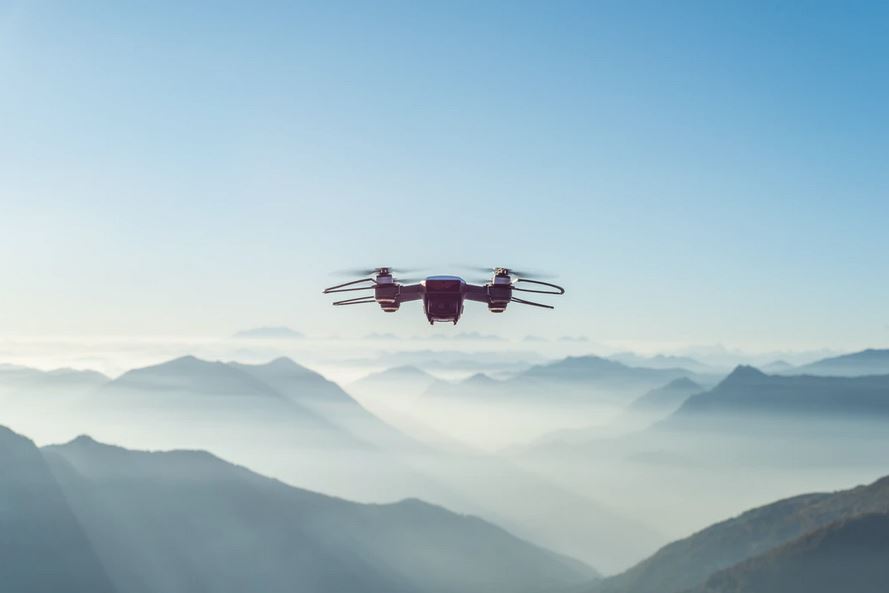 un drone en plein vol avec les montagnes et nuages en arrière plan
